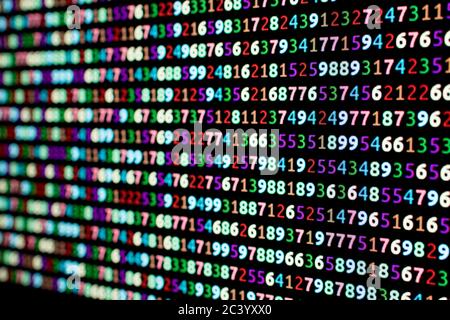 Series of colored numbers on a computer monitor with blur in the background. Sequence of numbers with bright colors on a black background Stock Photo