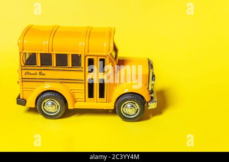 Simply design yellow classic toy car school bus isolated on yellow colorful background. Safety daily transport for kids. Back to school concept. Education symbol. Copy space Stock Photo