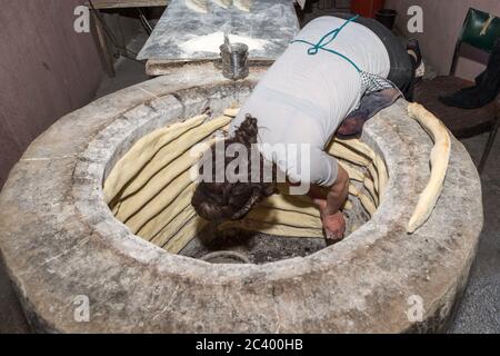 Placing the dough in the oven: Traditional bread baking and selling by local woman, Georgia Stock Photo