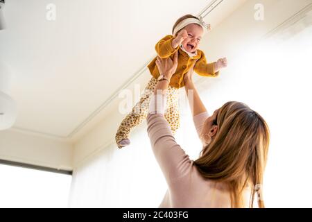 Beautiful family mother and baby daughter plays, hugging, kissing at home Stock Photo