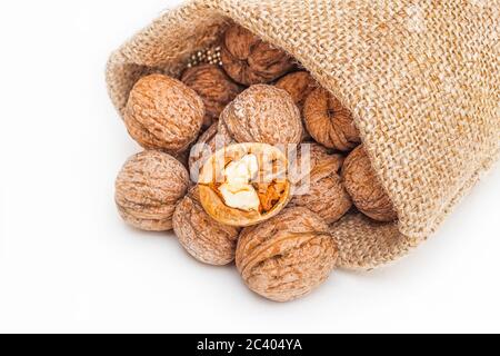 Close-up of wallnuts in a canvas sack with one opened wallnut on top. Isolated on white. Stock Photo