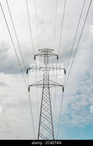 Single-circuit three-phase power transmission line transmission steel lattice tower or electricity pylon against white clouds at sky Stock Photo