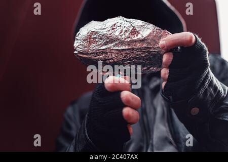 Drug addict smoking opium on tin foil, aka chasing the dragon, close up of hands with selective focus Stock Photo