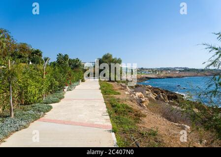 Bench on the promenade along the Mediterranean coast with Hotels. The concept of travel and recreation on the island of Cyprus. Stock Photo