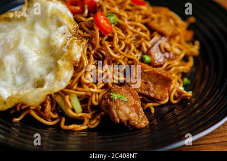 Dry Instant Noodle, Malaysian style maggi goreng mamak or spicy dry curry instant noodles with sunny side up egg and beef. Stock Photo