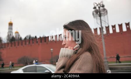 A girl in cloudy weather in autumn walks on the background of the Kremlin walls in Moscow. Stock Photo
