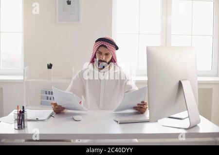 Serious Arabian businessman working with documents in office Stock Photo