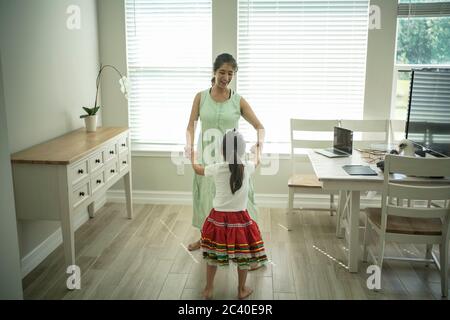 Girl enjoys an online dance class with a laptop connected to a TV at home Stock Photo
