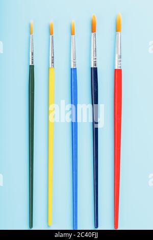 Brushes of different colors for drawing, creativity and art on a blue background. Stock Photo