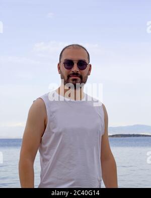 portrait of a handsome young man in sunglasses on the beach Stock Photo