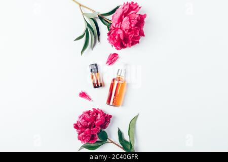 Floral flat lay composition natural beauty products serum and cosmetic oil next to fresh flowers and petals on white background with copy space. Stock Photo