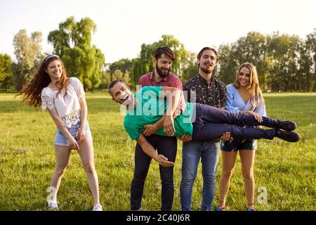 Friends having fun in wilderness during their summer trip in park. Group of people being silly outdoors Stock Photo