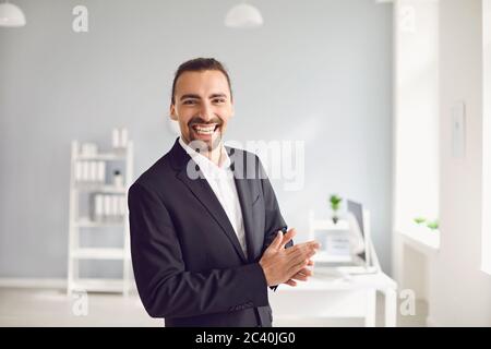 Happy businessman in formal suit standing in office Stock Photo
