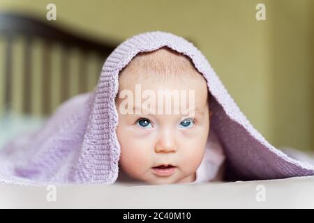 a beautiful newborn blue eyed girl lies on her tummy and looks up Stock Photo