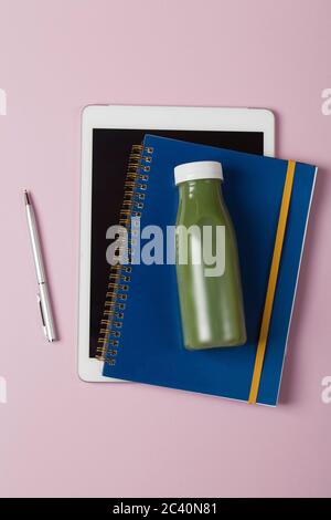 Healthy workspace with blue notebook laptop and green smothie on pink background Top View Flat Lay healthy food concept. Stock Photo