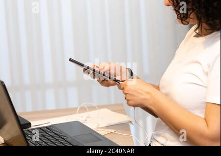 Close up of a woman hands plugging a charger on a smart phone at home or office. Stock Photo