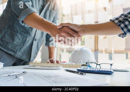 Architect and engineer construction workers shaking hands while working for teamwork and cooperation concept after finish an agreement in the office c Stock Photo