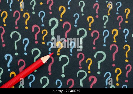 Colorful question marks with pen on a black paper. Close up. Stock Photo
