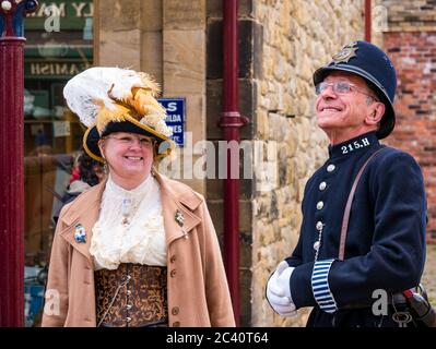 People dressed in period costume with man in  old fashioned police uniform and woman with feathered hat, Beamish Museum, Durham County, England, UK Stock Photo