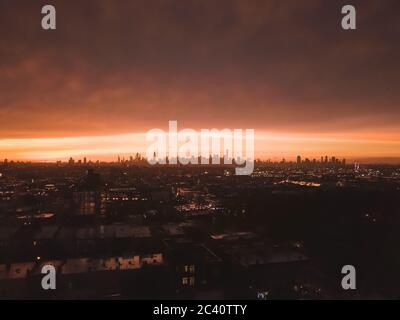 Aerial View from Brooklyn over far away Manhattan Skyline in the Distance after Sunset with Fire Red Light and Skyscraper Silhouette  Stock Photo