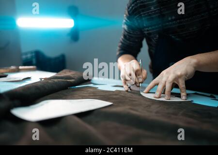 man shaping leather for shoe with knife on factory Stock Photo