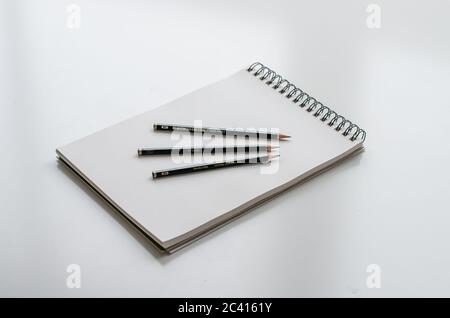 Blank Sketchpad with three pencils on a white desk Stock Photo
