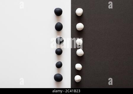 Black and white plasticine balls on contrasting sides of background. Concepts of racism and division, contrast in colors representing difference ideol Stock Photo