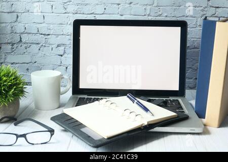 Laptop with blank screen with coffee mug and books on table  Stock Photo