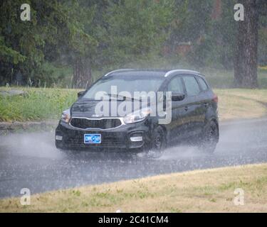 Car with new Ontario license plate driving in heavy rain storm on streets along Canal in Ottawa Stock Photo