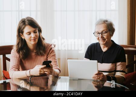 granddaughter using mobile and grandmother using tablet Stock Photo