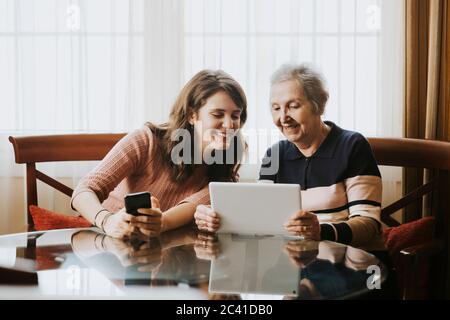 grandmother teaching her granddaughter something on the tablet Stock Photo