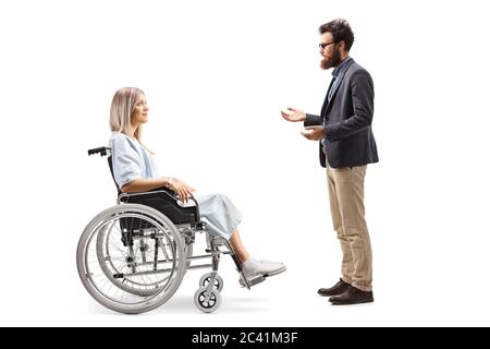 Full length profile shot of a hospitalized female patient in a wheelchair and a bearded man talking isolated on white backgraund Stock Photo