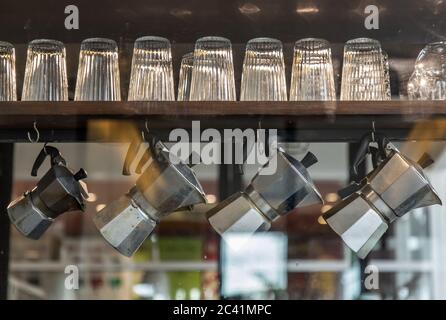 Interior design of coffee shop with glasses and moka pots. Moka pots are hanging on wooden rail. Selective focus Stock Photo
