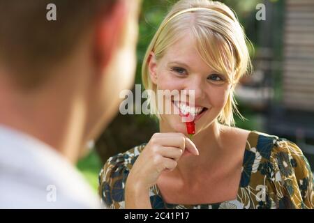 Young woman bites into a chilli pepper Stock Photo