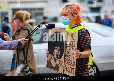 Richmond, North Yorkshire, UK - June 14, 2020: A white female protester at a Black Lives Matter rally holds a homemade anti racism sign while being in Stock Photo