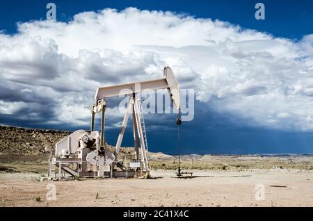 Oil pump in the desert with dark clouds of a thunderstorm looming in the background Stock Photo