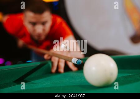 A young caucasian man in a red T-shirt is playing billiards Stock Photo