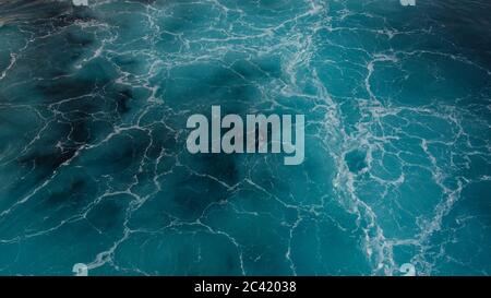 Turquoise blue sea or ocean waves creating a marble effect with white flowing lines and blue marine, navy tones visible in the crystal clear water Stock Photo