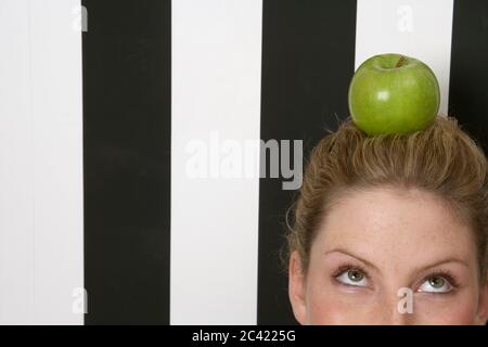 Young woman balances an apple on her head Stock Photo