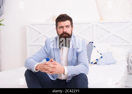 On wedding anniversary. Bearded man in wedding style sit on bed. Hipster wait in wedding suite. Formalwear and party wear. Fashion and style. Wedding shop. Stock Photo