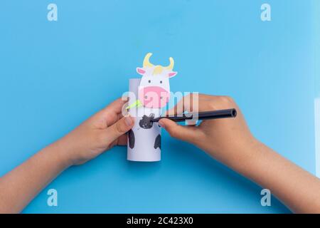 cow craft concept for kid and kindergarten, year of the ox, how to make cow, step by step instruction, tutorial, DIY, toilet paper roll craft, barnyard animal, colorize, kids hands, easy fun project Stock Photo