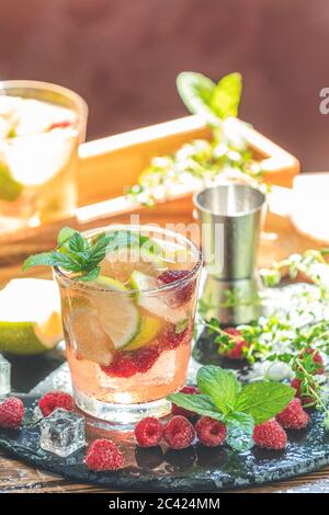 Refreshing mint cocktail mojito with rum, lime, mint, thyme, ice and raspberry. Alcohol or non alcohol summer fresh drink. Stock Photo