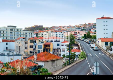 Aerial Funchal cityscape, traffic on hill road, residential houses with red rooftops, Madeira, Portugal Stock Photo