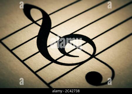 Black treble key or clef sign macro close-up printed on a musical chart or partition. Toned image. Stock Photo