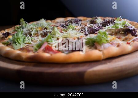 closeup pizza on a tray, with vegetables and meat, in a rustic style. Unusual angle. Salad, vegetable pizza, meat lunch. Friendly pizza. The texture Stock Photo