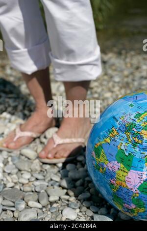 Feet with flip-flops next to a beach ball (globe), Munich, Bavaria, Germany Stock Photo