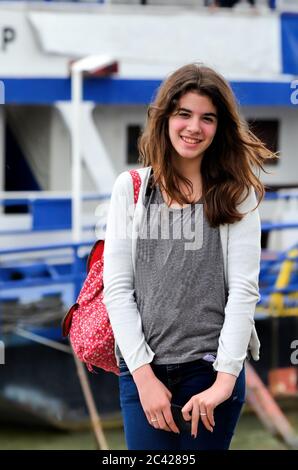 Teenage brunette girl wearing a jeans, with red backpack, ready to board the ship Stock Photo