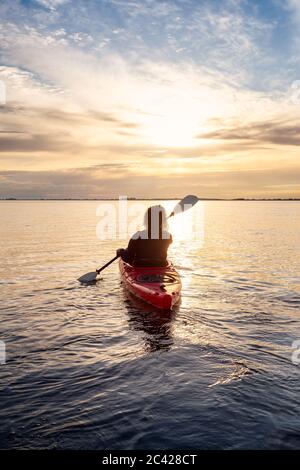 Sea Kayaking in calm waters during a colorful and vibrant sunset. Stock Photo