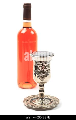 Filled Kiddush cup and a bottle of wine, isolated, shallow DOF Stock Photo