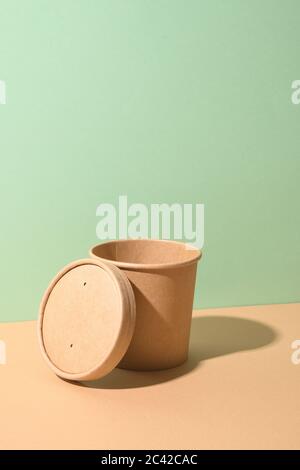 Craft paper soup cup with shadow on brown background. Empty container. Ecological individual package. Zero Waste. Stock Photo